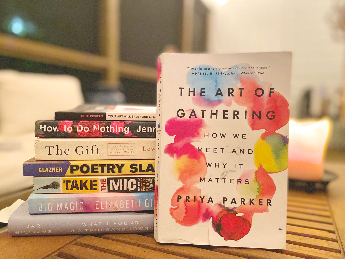 A stack of books for open mic hosts and organizers, with Priya Parker's The Art of Gathering displayed prominently