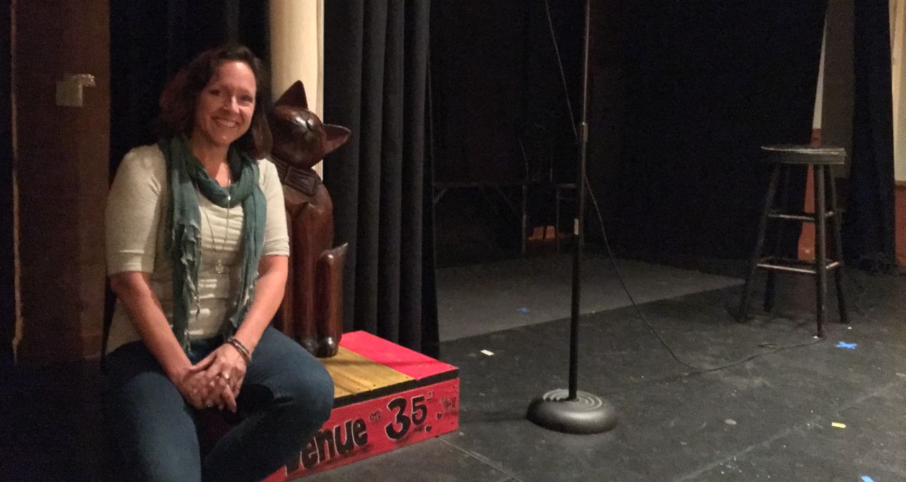 Anna poses with Aesop, a 3 ft tall wood statue of a friendly cat on a red pedestal with the words "Venue on 35th" painted on the base.